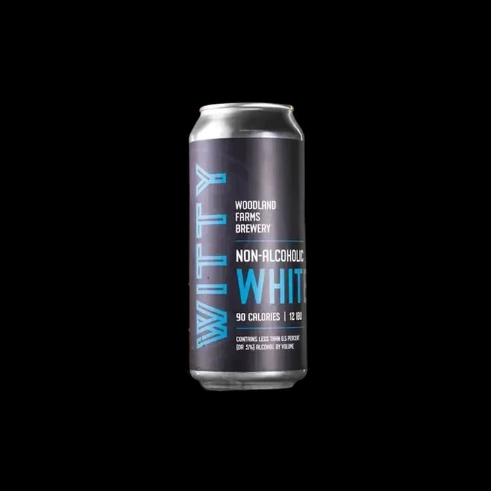 Woodland Farms Witty White non-alcoholic wheat beer, featuring a clove and banana aroma, against a plain background.